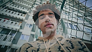 Portrait latin guy looking camera in front high residential building. Man posing