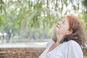 Portrait of a latin senior woman smiling looking up daydreaming in nature