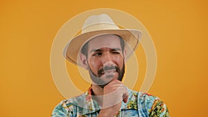 portrait of Latin young man who shakes his head suspiciously and smiles, horizontal isolated orange background