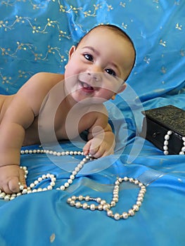 Portrait of a laughing baby boy with white pearls