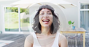 Portrait of laughing biracial woman outside on terrace of modern house in the sun
