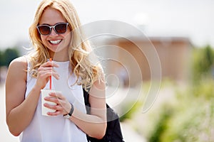 Portrait of laughing blond woman with refreshing drink outdoors