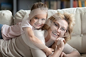 Portrait of laughing devoted mature woman holding on back kid.