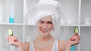 Portrait of laughing female in towel on head covered eyes by cucumber slice 4k footage