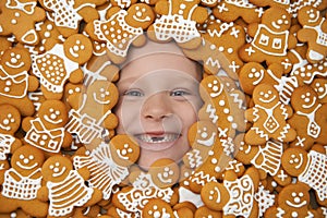 Portrait of the laughing girl surrounded by cookies with icing