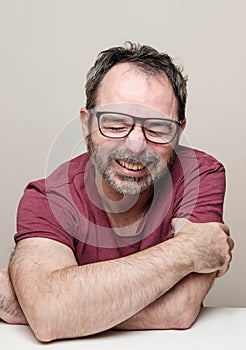 Portrait of a laughing mature man with beard wearing red t-shirt and glasses