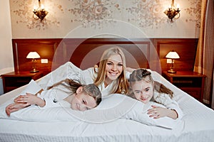 Portrait of a laughing mother and her twin children lying on a b