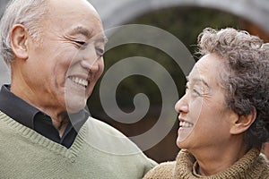 Portrait of laughing senior couple in front of round arch, Beijing