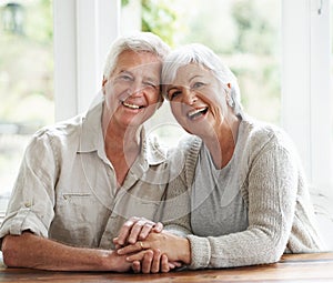 Portrait, laughing and senior couple holding hands for love, care and relax together at home. Face of happy old man