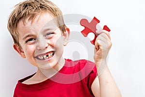 Laughing toothless boy finding jigsaw for concept of fun education photo