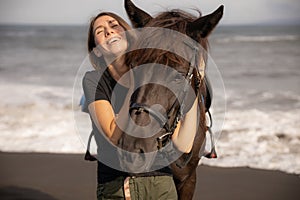 Portrait of laughing woman and brown horse. Young Caucasian woman hugging horse. Romantic concept. Love to animals. Nature concept