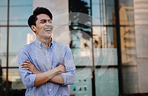 Portrait of Laughing Young Asian Businessman in the City. Crossed Arms and looking away. a Happy Man