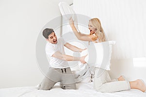 Portrait of a laughing young couple having pillow fight