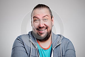 Portrait of laughing young man against grey wall. Happy guy smiling.