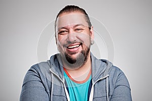 Portrait of laughing young man against grey wall. Happy guy smiling.