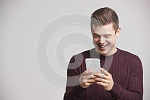 Portrait of a laughing young white man using a smartphone