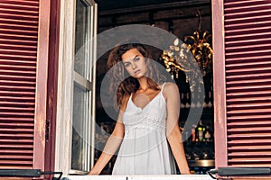 Portrait of laughing young woman looking through window of a cafe