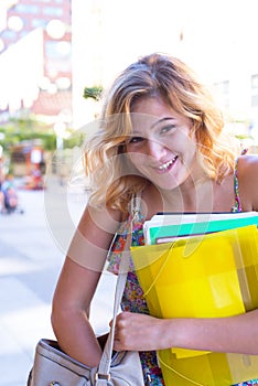 Portrait of a laughing young woman, student with colorful exercise books