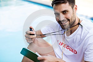 Portrait of lifeguard holding clipboard and stopwatch at poolside