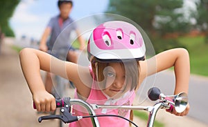 Portrait of a litte girl in a pink safety helmet driving her bike.