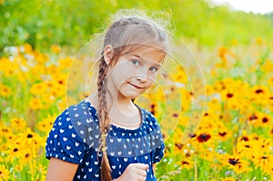 Portrait of a little adorable little girl smiling, in field with yellow flowers