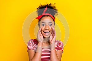 Portrait of little adorable schoolgirl hands near mouth say tell secret message news isolated on yellow color background