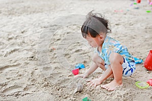 Portrait of little asian baby boy play sand with toys on beach