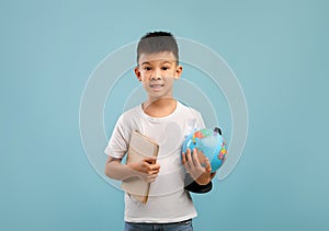 Portrait Of Little Asian Boy Holding Book And World Globe