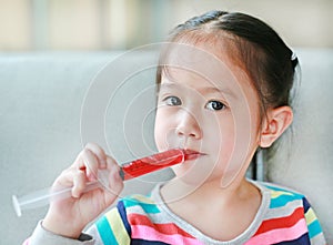 Portrait of little Asian child girl feeding liquid medicine with a syringe by self