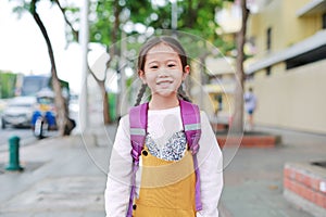 Portrait little Asian child girl with student shoulder schoolbag walking on walkway go to school. Back to school concept