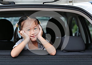 Portrait of little asian child looking camera from the hatchback door of the car