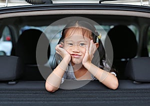 Portrait of little asian child looking camera from the hatchback door of the car