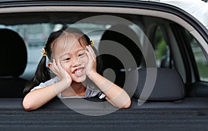 Portrait of little asian child looking camera from the hatchback door of the car