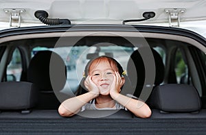 Portrait of little asian child looking camera from the hatchback door of the car