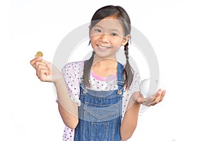 Portrait of little Asian girl holding piggy bank on white