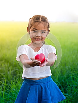 Portrait of little asian girl holding red heart and smilling.