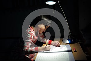 Portrait of little Asian girls doing her homework under the lighting lamp