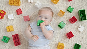 Portrait of little baby boy chewing and biting colorful toys while hes teeth is growing. Concept of children development