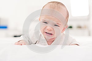 Portrait of little baby boy crying while lying