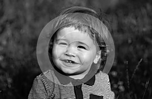 Portrait of a little baby boy playing outdoor in the grass. Baby face close up. Funny little child closeup portrait