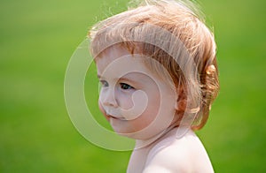 Portrait of a little baby boy playing outdoor in the grass. Baby face close up. Funny little child closeup portrait