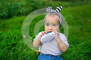 Portrait of a little baby chews his shoe on a grass