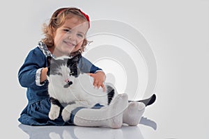 Portrait of Little baby girl holding her fluffy cat on white background