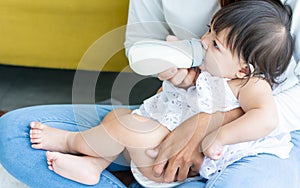 Portrait little baby girl wearing white clothes, drinking milk from bottle with lullaby, sleeping with happiness and comfortable