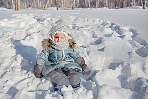 Portrait of little baby sits on snow in winter