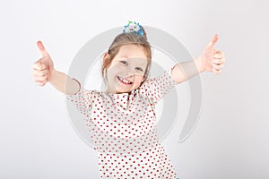 Portrait of little beautiful and confident girl showing thumbs