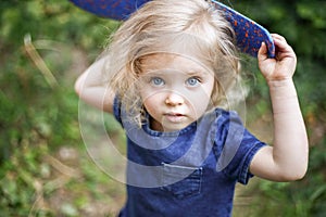 Portrait of a little beautiful European girl with curly blonde hair and blue eyes of 3 to 4 years in a classic blue color dress,
