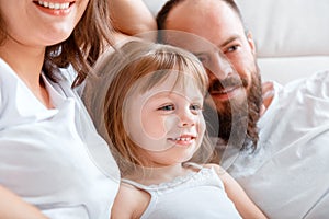 Portrait of little beautiful girl child kid surrounded by her family mom and dad. Young family spend time together hugs
