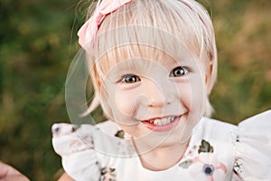 Portrait of a little beautiful girl on nature on summer day vacation. child in dress is playing in the green park at the