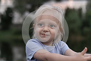 Portrait of little blonde girl with big eyes wears blue T-shirt and looks into the distance. Childlike spontaneity